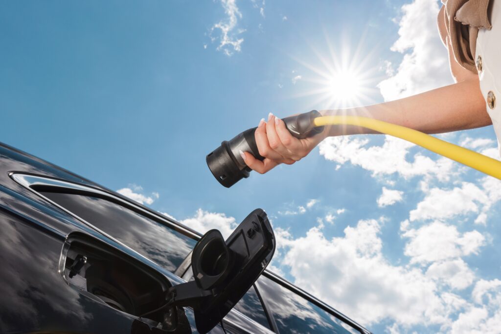 woman,plugging,in,the,charger,into,electric,car,at,a woman,plugging,in,the,charger,into,electric,car,at,a